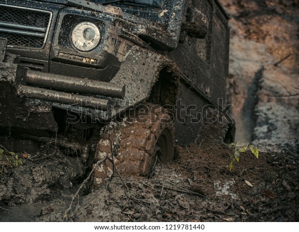 4x4 or 4WD car with wheels in mud in the forest,\
off road. Car stuck in puddle of mud. Wheel covered with dirt.\
Extreme entertainment\
concept.