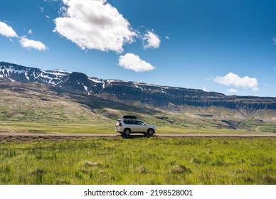 4x4 car parked on dirt road among the mountain and meadow on sunny day in summer at Iceland