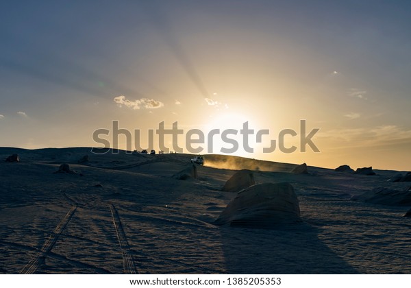 4x4 car in sahara desert at sunset with people\
watching the setting sun