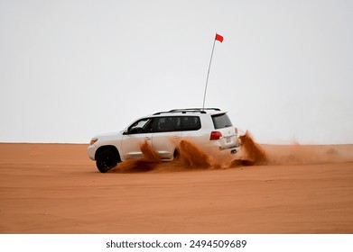 4x4 cars drift across Saudi Arabia’s striking red sand desert. The vehicles perform thrilling maneuvers, sending sand flying in dramatic arcs against the backdrop of the vast vibrant dunes near Riyadh - Powered by Shutterstock