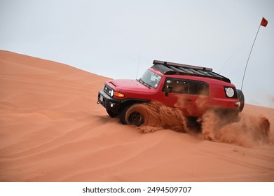 4x4 cars drift across Saudi Arabia’s striking red sand desert. The vehicles perform thrilling maneuvers, sending sand flying in dramatic arcs against the backdrop of the vast vibrant dunes near Riyadh - Powered by Shutterstock