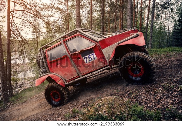 4x4 jeep SUV car drives into a
hill in the forest in an off-road race in summer on a sunny
day