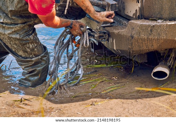 The 4x4 off road\
got stuck in a huge puddle of mud. Extreme car sports. An athlete\
prepares a winch for the evacuation of a four-wheel drive car from\
a trap. Selective focus