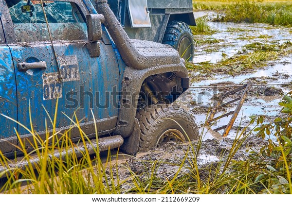 4x4 SUV stuck in a swamp during extreme\
competitions is pulled out using a winch. Off-road car racing.\
Off-road car in action. Concept of extreme travel, adventure or\
tourism in picturesque\
places