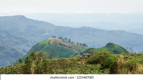 4x4 vehicle in rolling fertile hills with fields and crops on Ring Road of Cameroon, Africa.