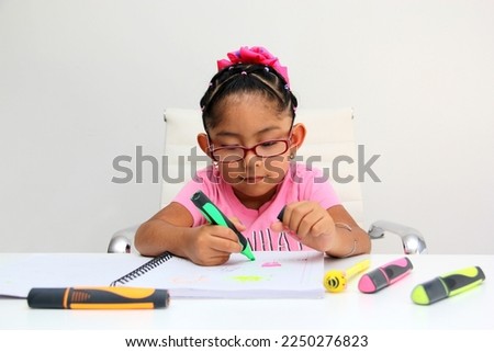 4-year-old brunette Latina girl with autism spectrum disorder ASD like Asperger, Rett and Heller draws at a desk, plays with colors alone antisocial