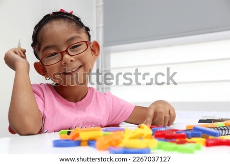 4-year-old brunette Latina girl with autism spectrum disorder ASD like Asperger, Rett and Heller draws at a desk, plays with colors alone antisocial