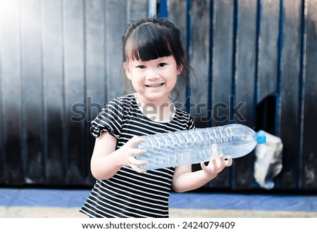 A 4-year-old child holds a plastic bottle to show how to reduce global warming. Separating waste for recycling Reduce the destruction of air pollution