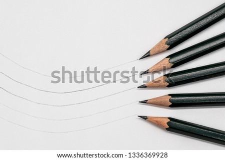 5 artist pencils lying on white paper, example line thickness