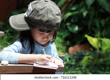 5 Year Old Asian Girl In Her Backyard Nature Class,looking,observe For The Tree Components.Girl Drawing And Take Noted What She Finding.Nature Classroom Make Independence And Self-esteem In Children. 