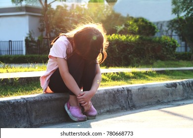 5 Year Old Asian Little Girl Sit Alone At The Street In The Evening.Girl Hide Her Face On Her Knees,she May Crying Or Ignoring.Concept Of Lonely Child Or Kid In Trouble Or Kid Violence.