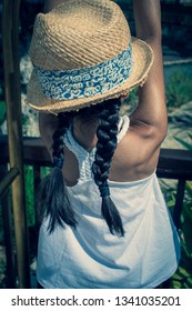 A 5 Year Old Girl In A Sunhat And Sunglasses Plays On The Luggage Rack Of A Bellboy, Outside A Holiday Hotel, Whilst On Vacation. 