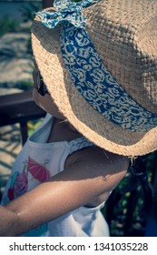 A 5 Year Old Girl In A Sunhat And Sunglasses Plays On The Luggage Rack Of A Bellboy, Outside A Holiday Hotel, Whilst On Vacation. 