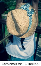 A 5 Year Old Girl In A Sunhat And Sunglasses Plays On The Luggage Rack Of A Bellboy, Outside A Holiday Hotel, Whilst On Vacation. 