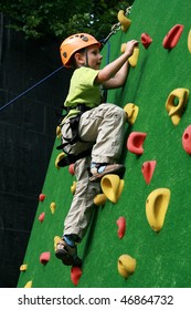 5 years old child climbing on a wall in an outdoor climbing center