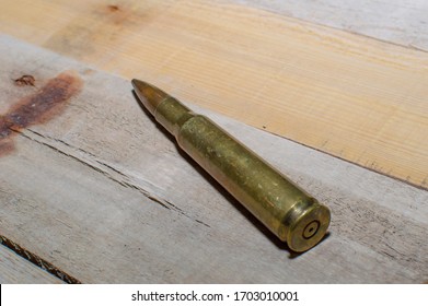 A 50 caliber rifle bullet laying on old barn wood.