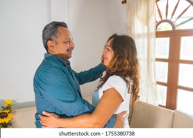 50 Year Old Spouses Dancing At Home, Smiling Feel Happy And Healthy Looking At Each Other, Portrait Of An Old Couple, Concept Of Lifetime Anniversary Together