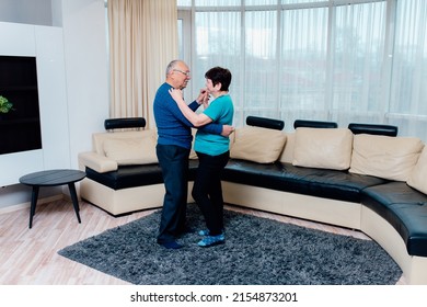 50 Year Old Spouses Dancing At Home, Smiling Feel Happy And Healthy Looking At Each Other, Portrait Of Modern Romantic Elderly Couple Is Hugging, Embracing Gently