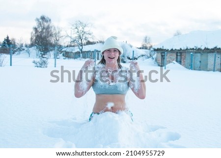 50 year old woman enjoying in swimsuit, in snow drifts. The concept of hardening, winter swimming happy healthy lifestyle 