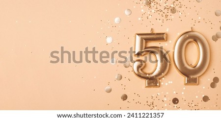 50 years celebration. Greeting banner. Gold candles in the form of number forty on peach background with confetti.