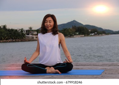 50 Years Old Thai Woman Is Meditating At Pier