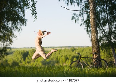 50 Years Old Woman With Bicycle Jumping In  Birch Forest At Summer