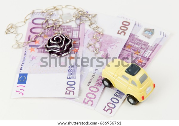 500 Euro bank notes, car and jewelry. Concept of\
consumerism and money\
spending