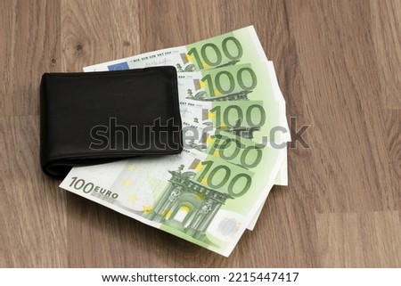 500 euros sticking out of the wallet. Five paper banknotes of 100 euros each. Symbol for growing expenses, inflation, paying household bills, salary, pay rise, salary increase, bonus, winning, lottery