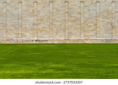 A 50-50 split composition: vibrant green lawn below, textured marble wall above at Pisa's cathedral complex. Minimalist architectural photography. Pisa,Italy 

