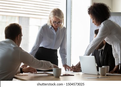 50s Business Woman Lead Group Meeting With Multi-ethnic Staff In Boardroom, Diverse Colleagues Working Together Planning At Morning Briefing Preparing Report Presentation For Client, Teamwork Concept