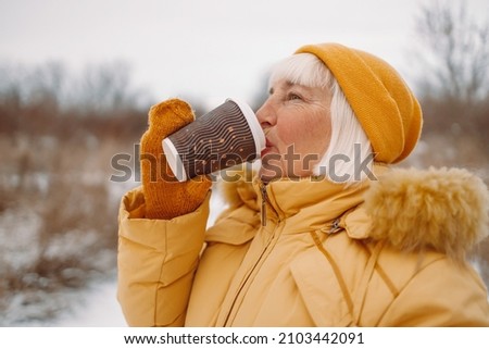50s tourist woman drinking hot takeaway cup of coffee enjoying on winter street