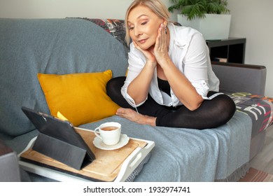 50s Years Old Woman Sit At Home On Sofa And Look To The Tablet, Drink Tea.