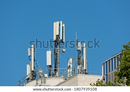 5G and 4G mobile phone antennas installed on the rooftop of a building. Blue sky