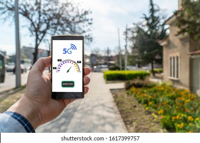 5g Network Street Speed Test. Man Holding A Smartphone Outside And Checking The 5g Speed.