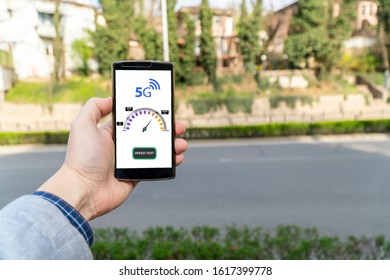 5g Network Street Speed Test. Man Holding A Smartphone Outside And Checking The 5g Speed.