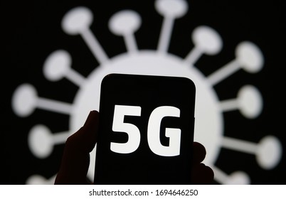 5G radiation in a shape of COVID-19. 5G letters on smartphone silhouette hold in a hand and coronavirus image on the background. Real photo, not a a montage. 5G conspiracy fake news, arson concept. 