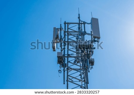 A 5g tower with complex array of equipment such as antenna's, distribution boxes, and remote radio units on a heavy lattice mast