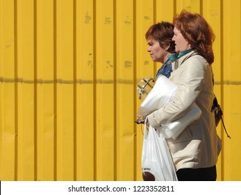 5th of May 2018 - Scene from Russian city with close up of  two women passing a yellow wooden wall, Kingisepp, Russia - Shutterstock ID 1223352811
