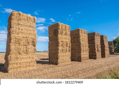 6 Bales Of Hay Stacked High In A Field With Blue Sky On A Sunny Day