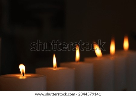 6 candles burning a flickering light in against darkened backgrond. Candle light vigil for remembering victims of crie or lost relatives. 
