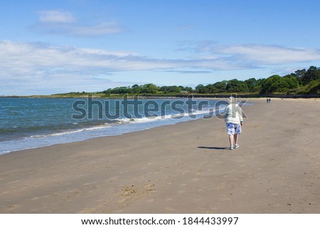 6 June 2020 An elderly woman and others walk the beach for exercise during the Corona Virus pandemic at Ballyholme in Bangor Northern Ireland on a breezy summer's day
