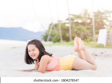 6歳のアジア人女の子が横になってリラックスして海辺で彫刻の白い砂を遊びます。休暇とリラックスのコンセプト夏休みと子育てのビーチで遊ぶ活発な子ども。アジアの女の子の笑顔。