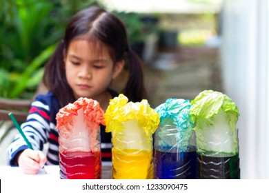 6 Years Old Asian Kid  Making Simple Science Experiment At Home.Girl Making How Plants Absorb Water And Nutrients Up Through Their Stems By Using  Cabbage Leaves And Food Coloring.She Taking A Noted. 