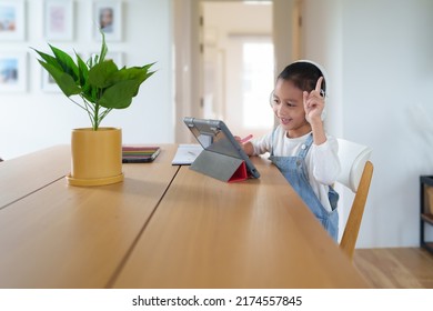 A 6 Years Old Asian Little Student Girl Is Using Tablet For Online Learning Classroom. Concept Of Technology, Internet, Connection, Distance Learning In Worldwide Education And Homeschooling For Kid.