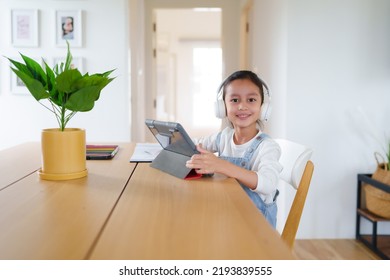 A 6 Years Old Asian Little Student Girl Is Using Tablet For Online Learning Classroom. Concept Of Technology, Internet, Connection, Distance Learning In Worldwide Education And Homeschooling For Kid.