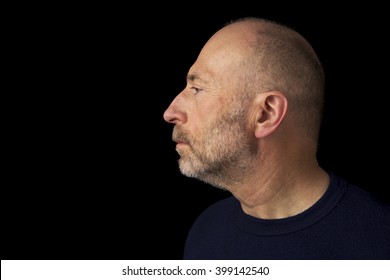 60 Years Old  Bald Man With A Beard - A Profile Headshot Against A Black Background