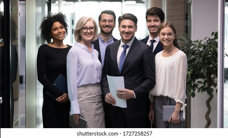 60s And Millennial Company Staff Members Standing In Hallway Photo Shooting For Corporate Album. Six Successful Office Workers Firm Representatives Ready For Negotiations Meeting With Client Concept