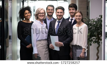 60s and millennial company staff members standing in hallway photo shooting for corporate album. Six successful office workers firm representatives ready for negotiations meeting with client concept