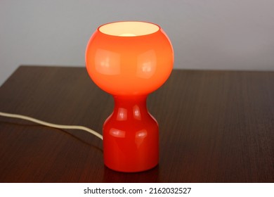 A 60s Modern Orange Bedside Lamp With Glass Spaceage Vintage Midcentury Design Front Side View Isolated On White Background With Warm Orange Light In The Studio Living Room Creative HQ 60s Furniture