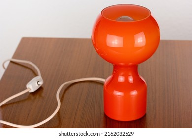 A 60s Modern Orange Bedside Lamp With Glass Spaceage Vintage Midcentury Design Front Side View Isolated On White Background With Warm Orange Light In The Studio Living Room Creative HQ 60s Furniture